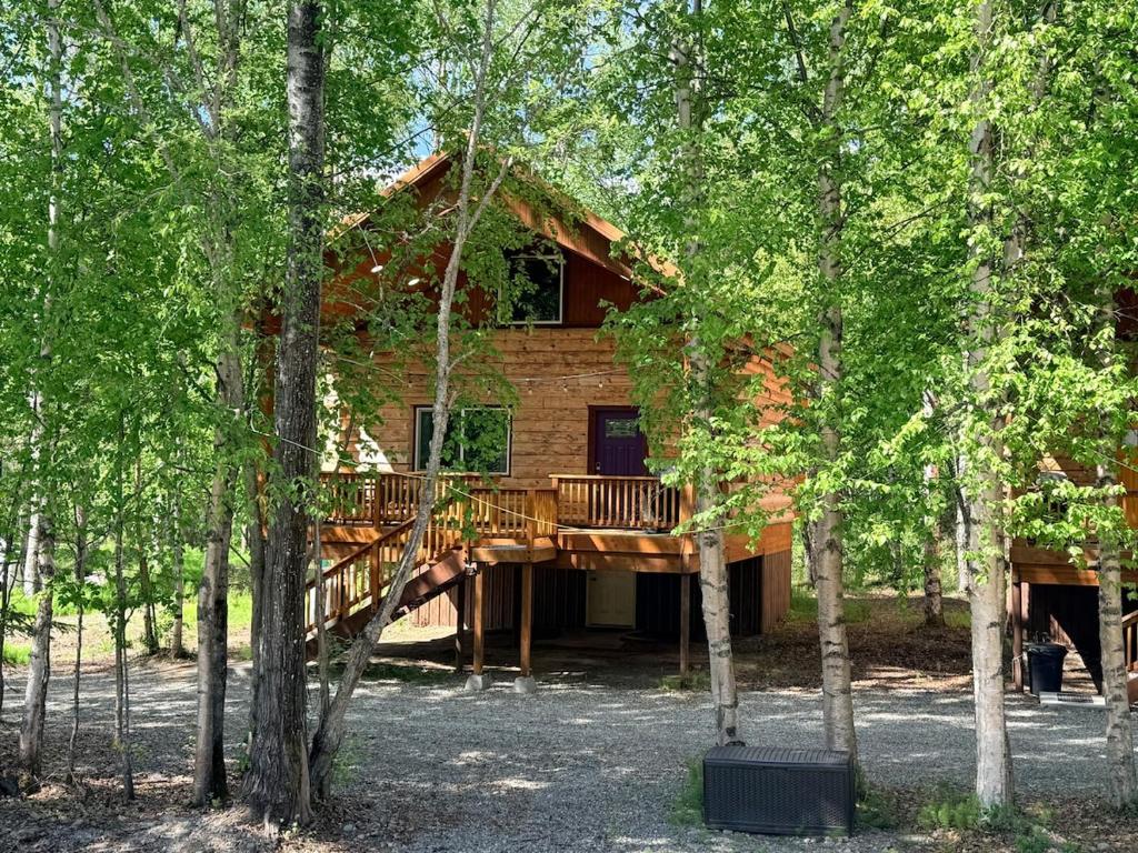 a log cabin with a deck in the woods at Riverfront, Authentic, Luxury Log Cabin-Gray Wolf in Wasilla