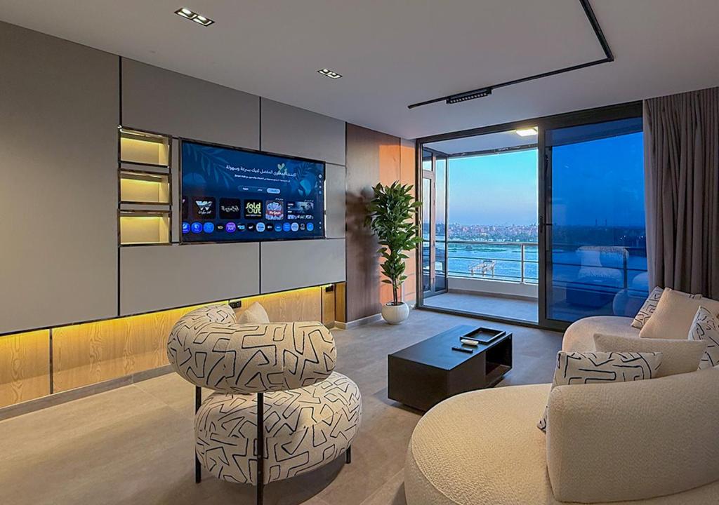 a living room with a couch and a chair and a tv at Panoramic Nile View 3BR Apartment in Cairo