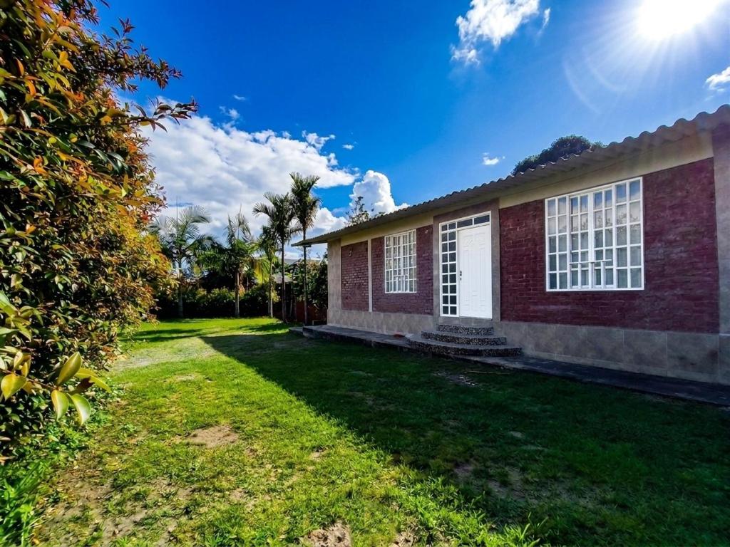 a house with a grass yard in front of it at ISA BELLA Hospedaje y Cabaña Entre Aves in Luna Park