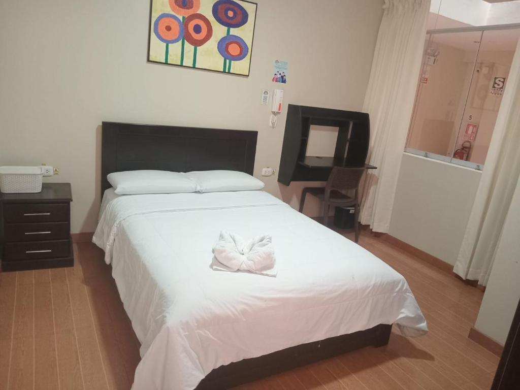 a bedroom with a large white bed with a bow on it at Paskary Hotel in Cajamarca