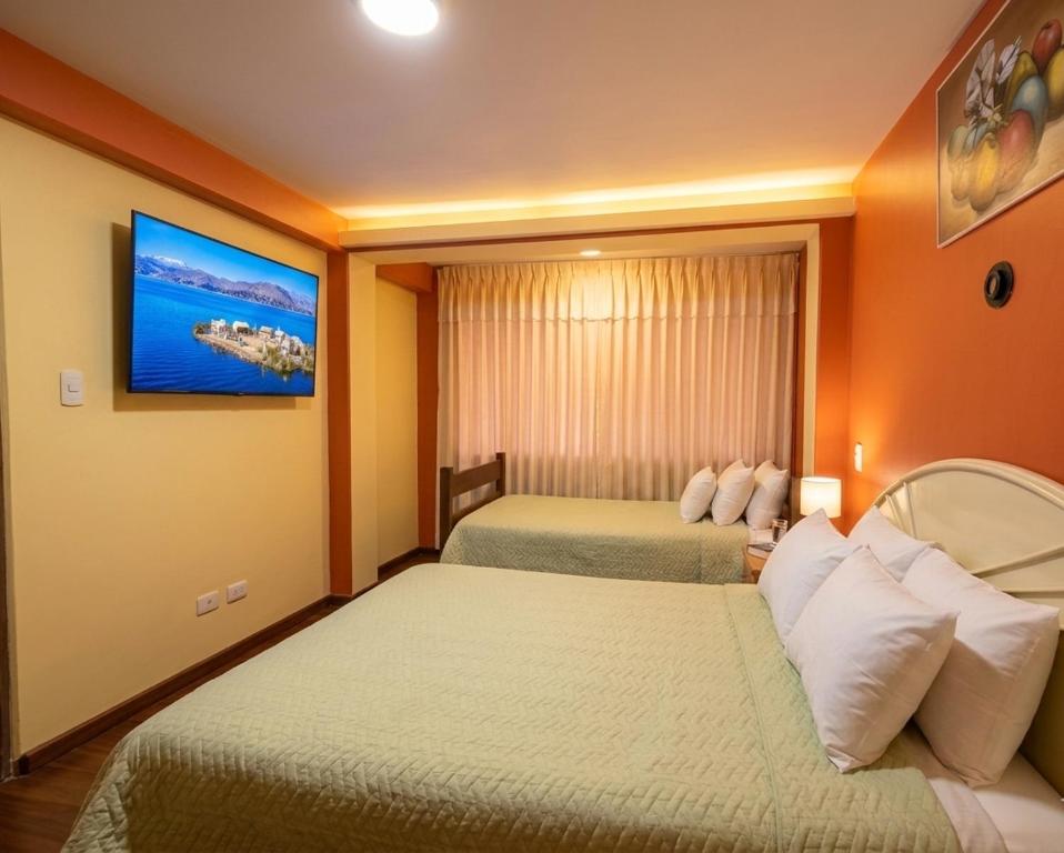 a hotel room with two beds and a tv on the wall at Andenes Perú in Puno