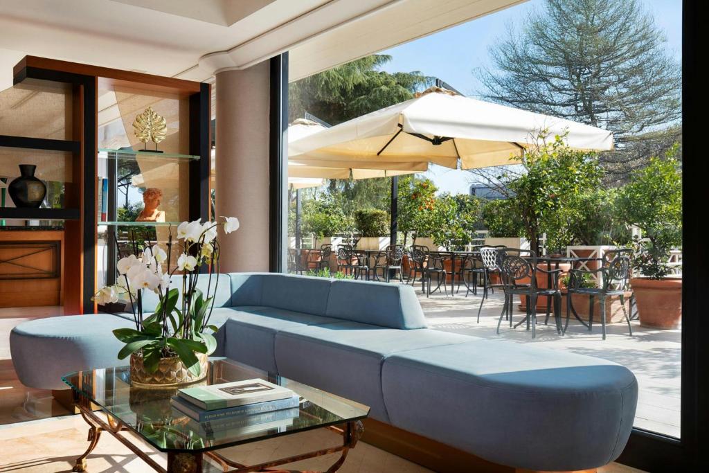 a living room with a blue couch and an umbrella at Courtyard by Marriott Rome Central Park in Rome