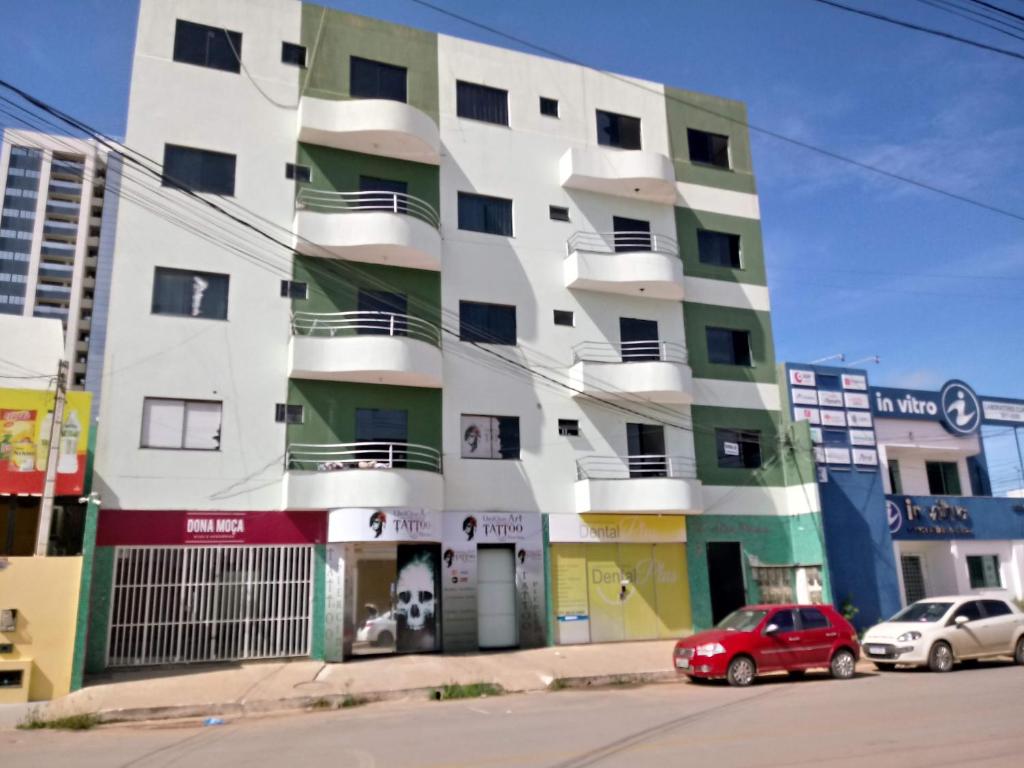 a tall white building with cars parked in front of it at Apt 402 Ed Nilson Pimentel in Barreiras