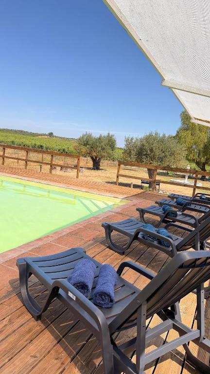a group of lounge chairs on a deck with a pool at Herdade do Corval in Reguengos de Monsaraz