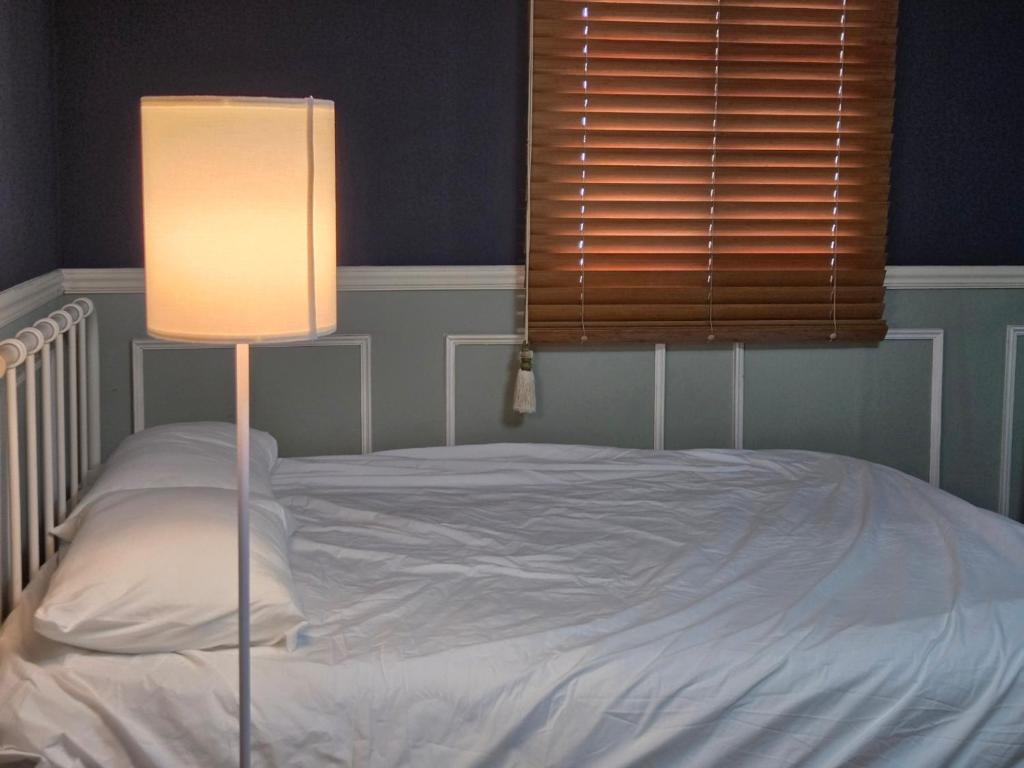 a bedroom with a bed with a lamp and a window at 지슬스테이 in Pyoseon
