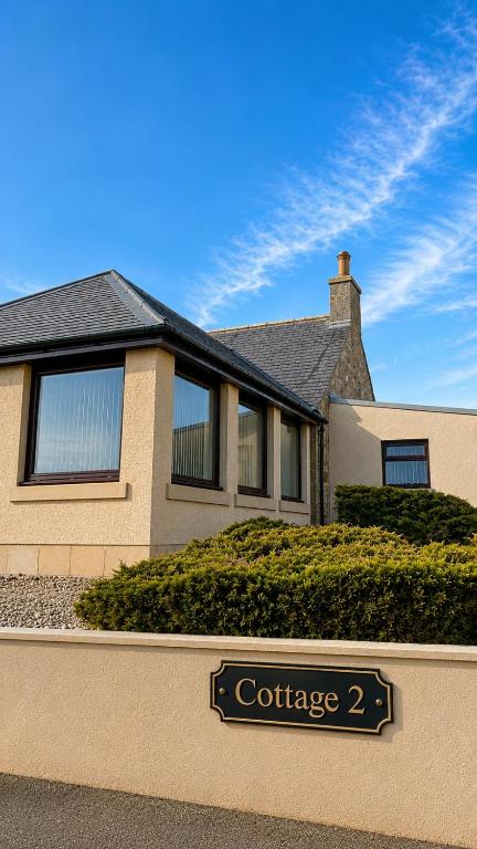 a house with a street sign in front of it at Burnside Holiday Cottage 2 in Fochabers