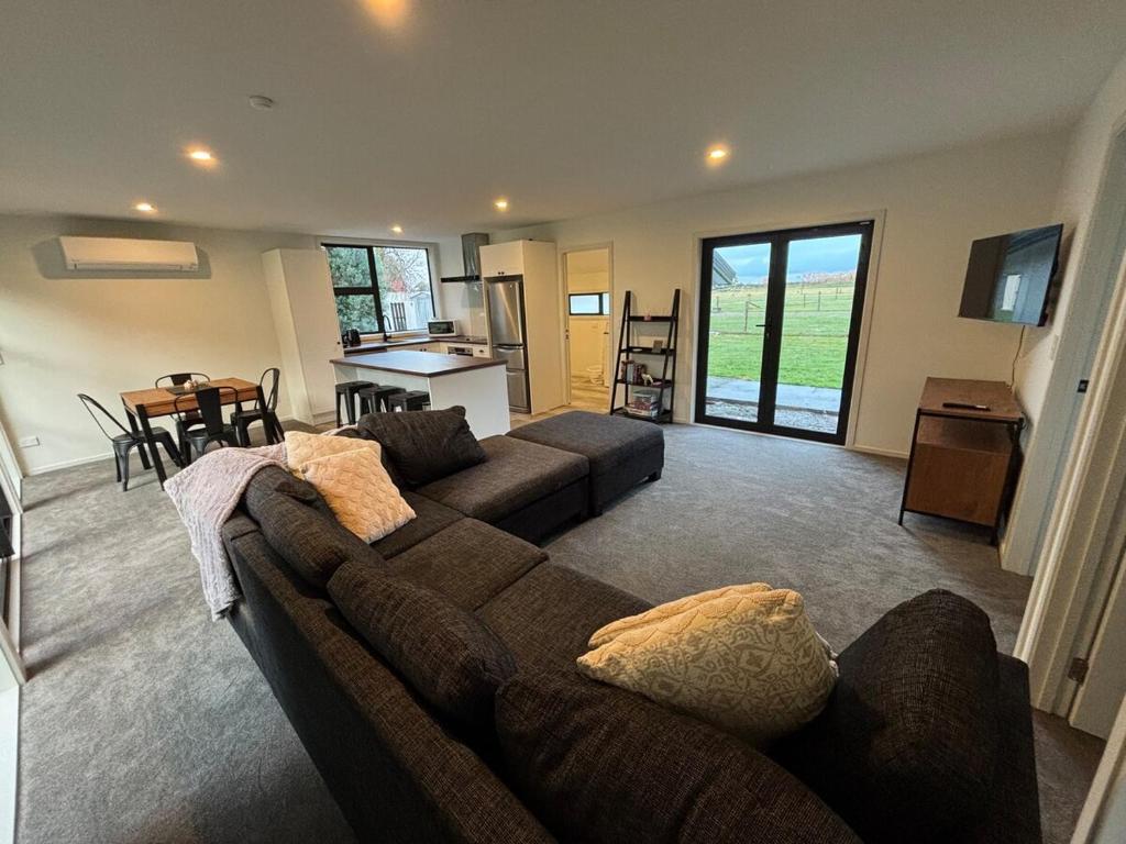 a living room with a brown couch and a kitchen at Cottage Lifestyle in Fernside