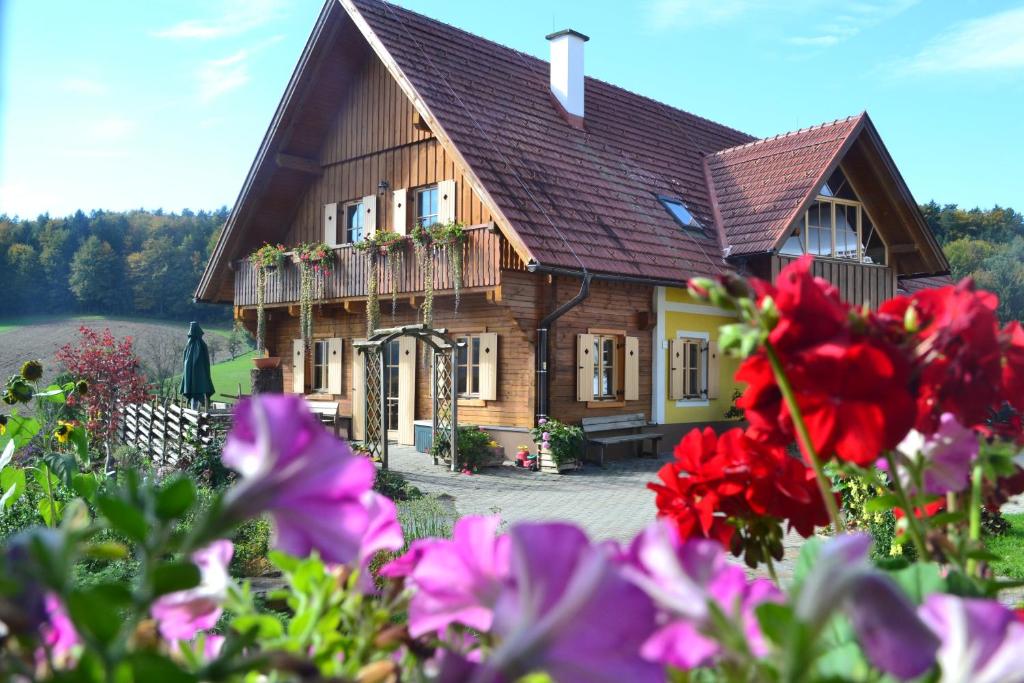 uma casa de madeira com flores em frente em am Jaukhof Familie Stiendl em Neudorf im Sausal