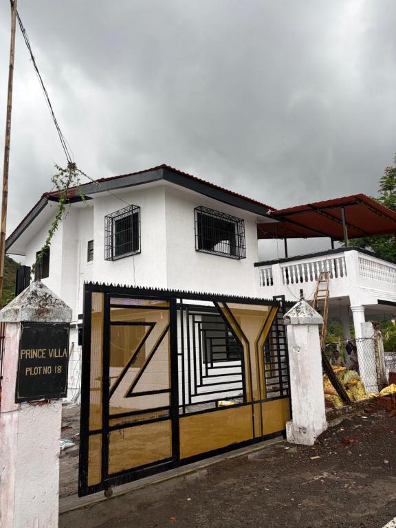a white and black house with a large door at Prince Villa in Neral