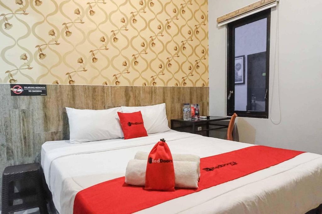 a bedroom with a bed with a red robe on it at RedDoorz @ Bukit Dieng 2 in Malang