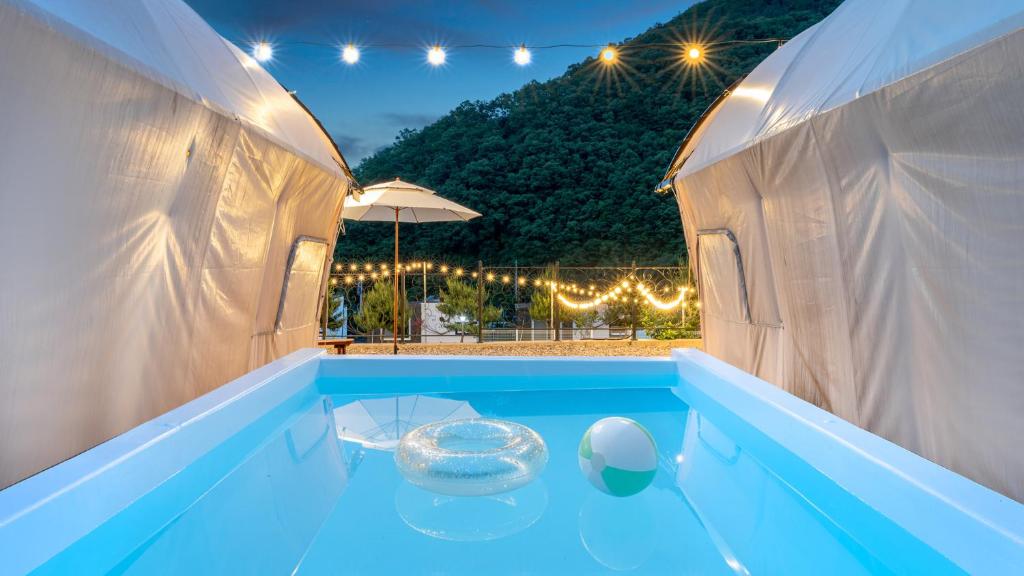 a large swimming pool with a blue floor and an umbrella at Mungyeong The Most Glamping in Mungyeong