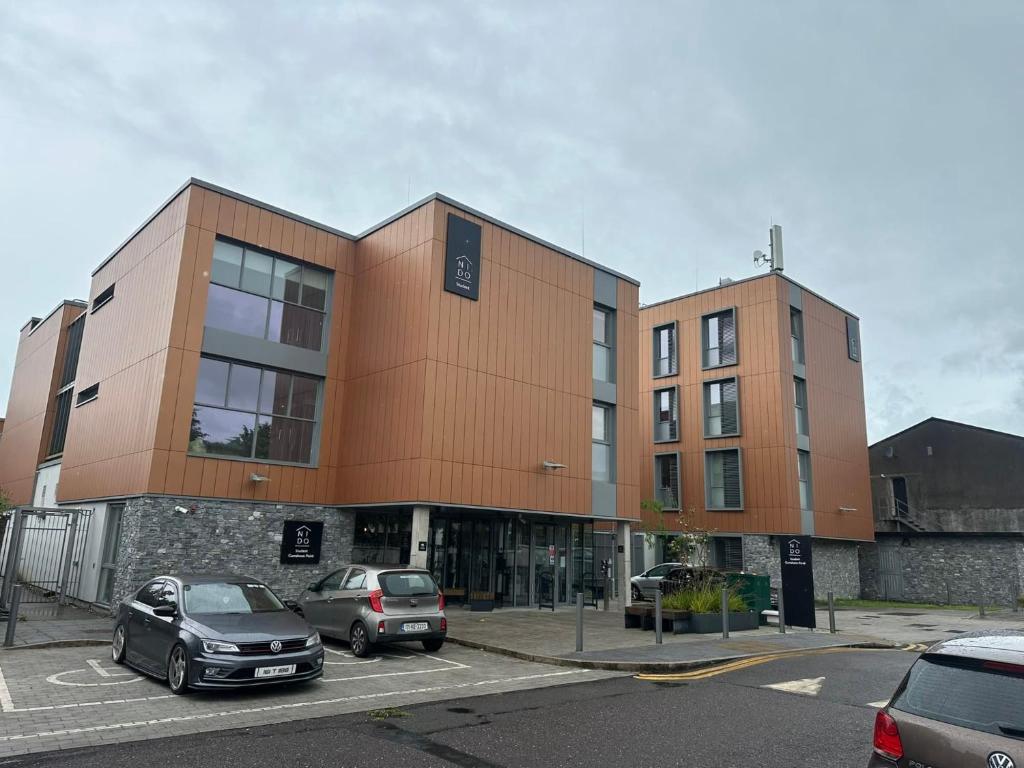 a building with two cars parked in a parking lot at Curraheen Point Cork - Easy Access to City Centre in Cork