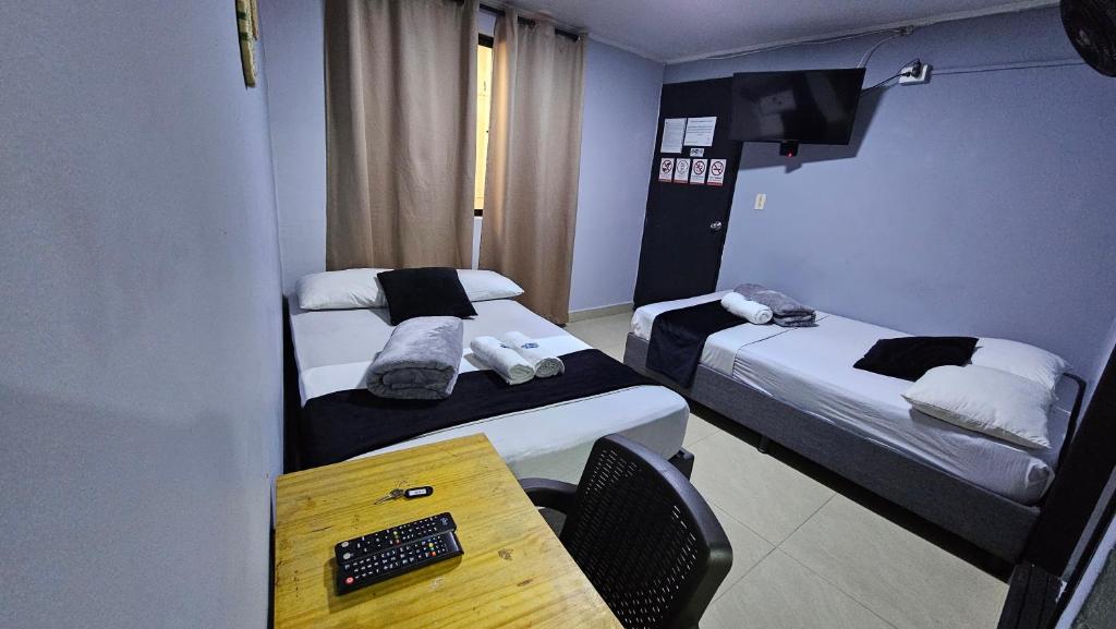 a room with two beds and a desk with a computer at aparta hotel continental estadio in Medellín