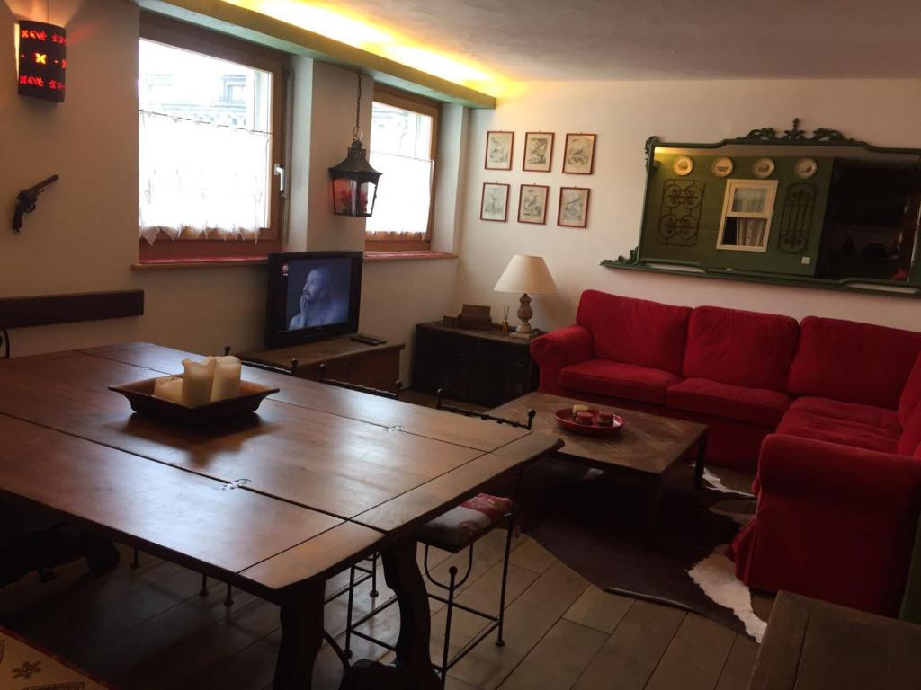 ein Wohnzimmer mit einem roten Sofa und einem Tisch in der Unterkunft meschihouse - Chesa Engadina in Samedan