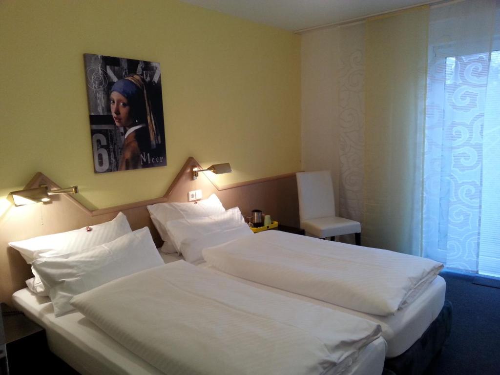 a hotel room with two beds and a picture on the wall at Hotel Garni Sand in Tübingen