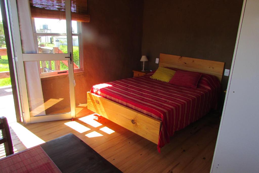 1 dormitorio con cama de madera y manta roja en Los Monos, en La Pedrera