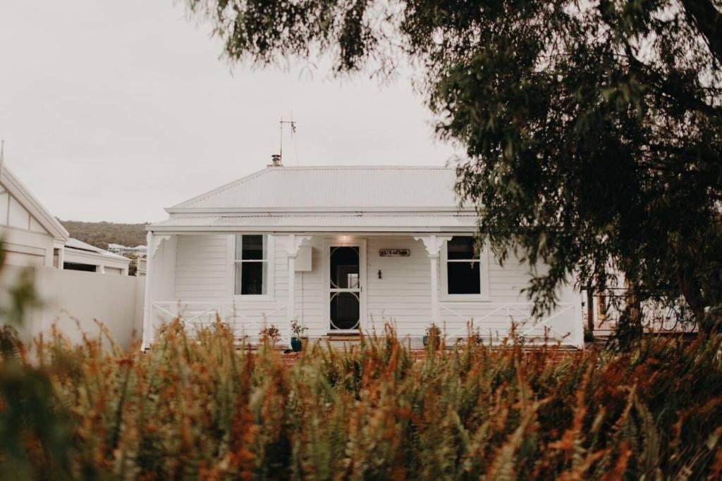 a white house with a door in a yard at Balnagown in Albany