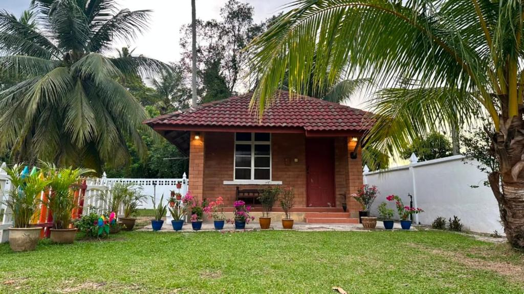 a small house with a palm tree in a yard at Homestay Sani in Tanah Merah