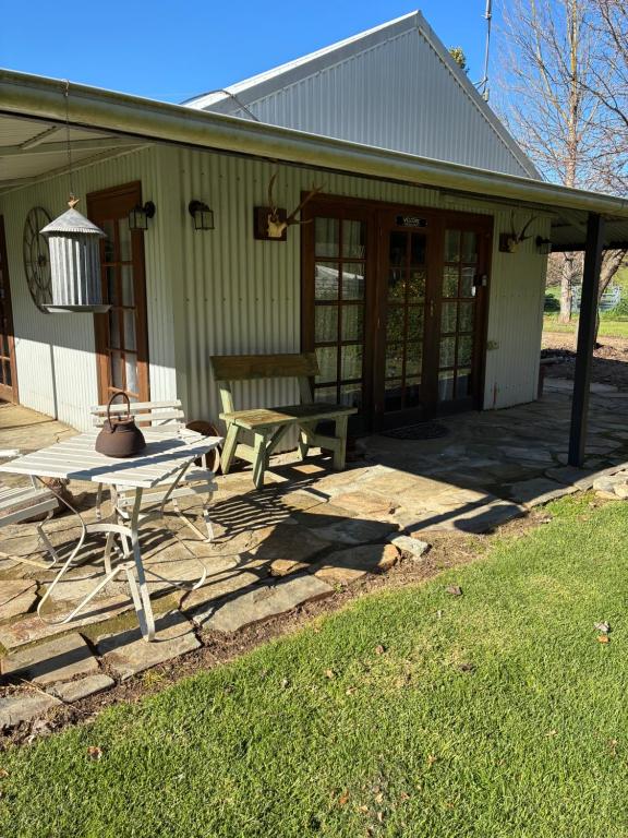 a house with a picnic table and a bench at Coppabella Cottage in Jingellic