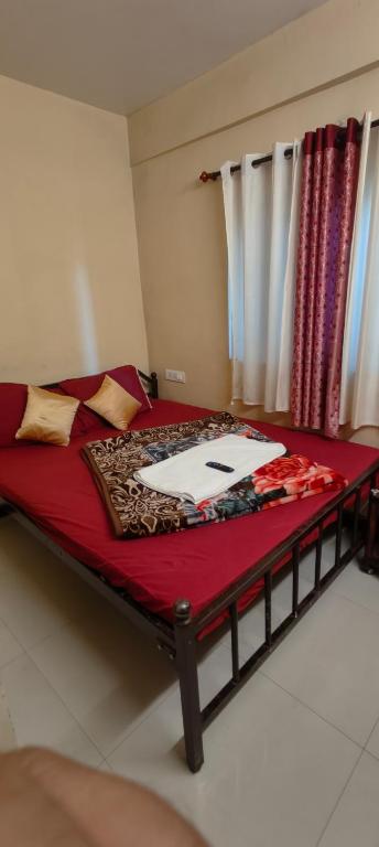 a bedroom with a bed with red sheets and a window at Yamuna rooms and dormitory in Ooty
