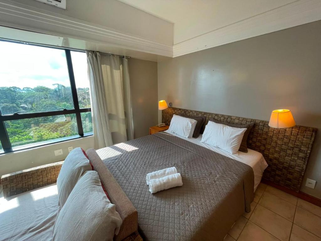 a bedroom with a large bed and a large window at Flat Tropical Hotel Vista Espetacular in Manaus