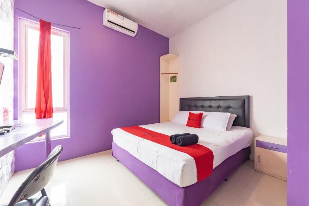 a purple bedroom with a bed and a desk at RedDoorz Plus @ Tuparev Cirebon 2 in Cirebon