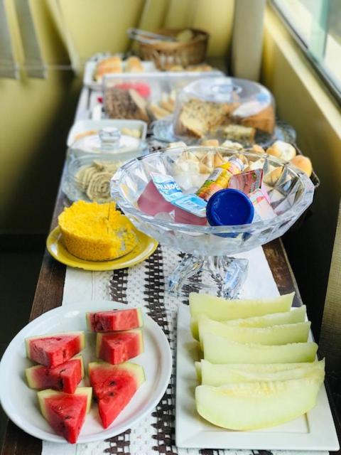 a long table with plates of food and fruit at Quarto privativo Pousada Luna in Fernando de Noronha