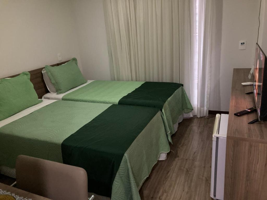 a bedroom with two beds with green sheets at Via Première - Suíte - Riocentro - Barra Olímpica - Vista Panorâmica in Rio de Janeiro