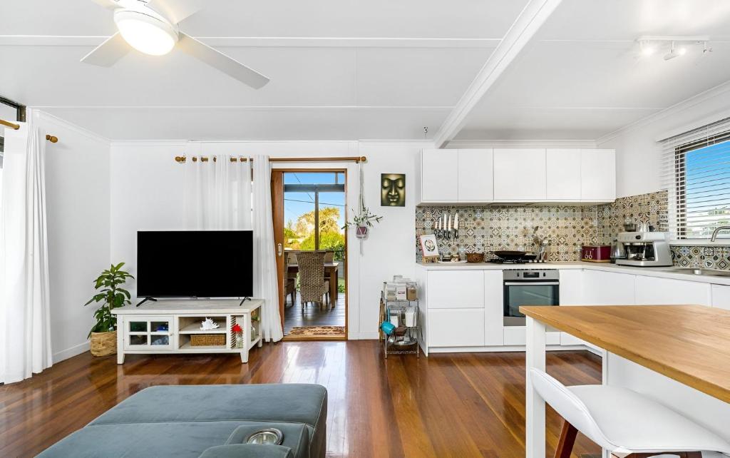 a kitchen with white cabinets and a flat screen tv at Ocean Hideaway in Kingscliff