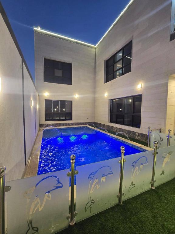 a swimming pool with dolphins painted on the side of a house at شالية ورد in Rayyis
