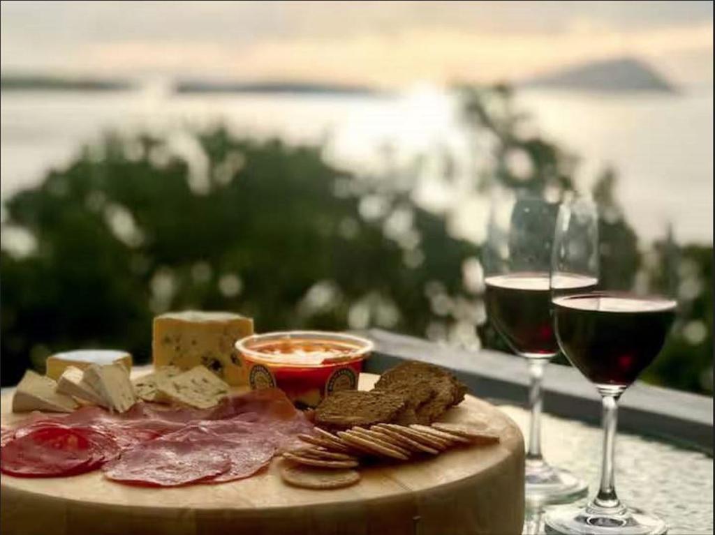 a plate of meat and cheese and two glasses of wine at Island view Experience in Coromandel Town