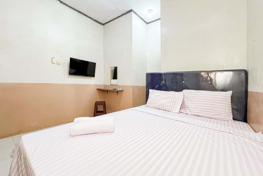 a large white bed in a room with a tv at Homestay E Rahayu Anyer RedPartner in Serang