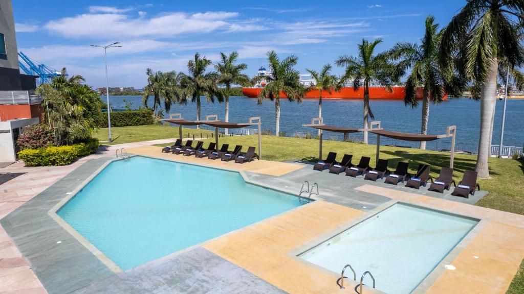 a swimming pool with chairs and the water at Holiday Inn Express - Tuxpan by IHG in Tuxpan de Rodríguez Cano