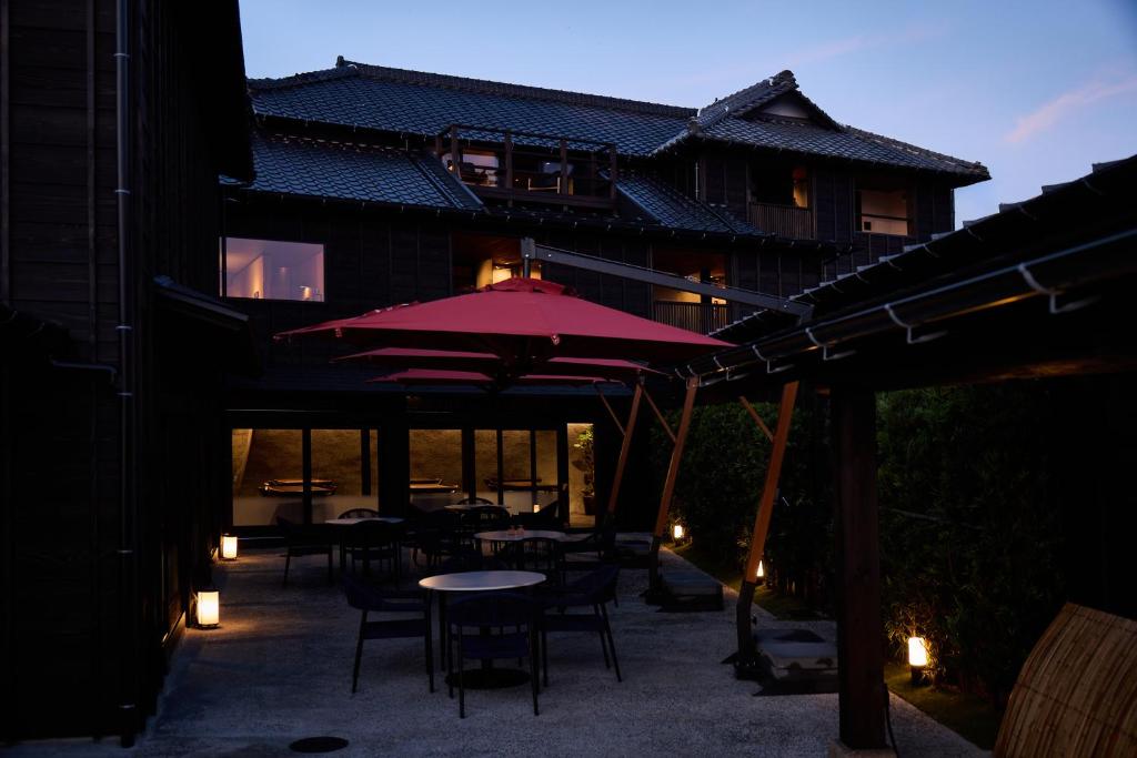 a patio with tables and chairs and an umbrella at いっぺ The Sake Ryokan in Kyonan