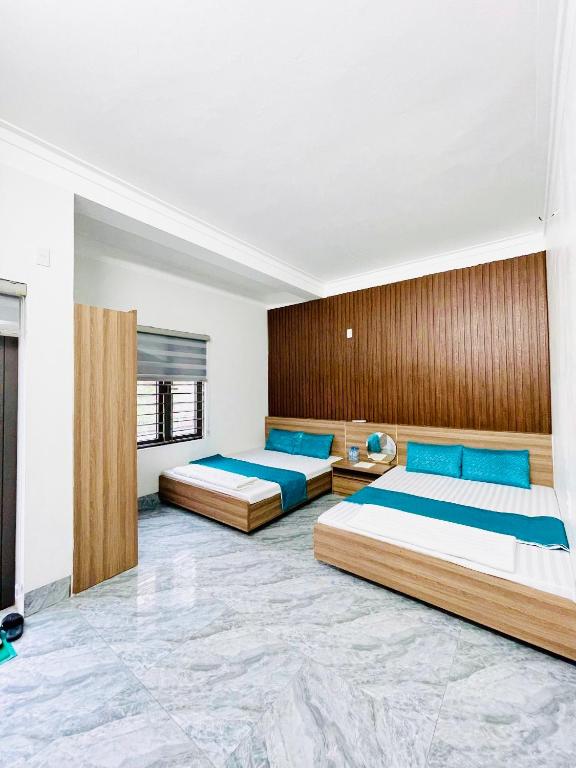 two beds in a large room with blue pillows at Nhà nghỉ Lena Quan Lạn in Quan Lạn