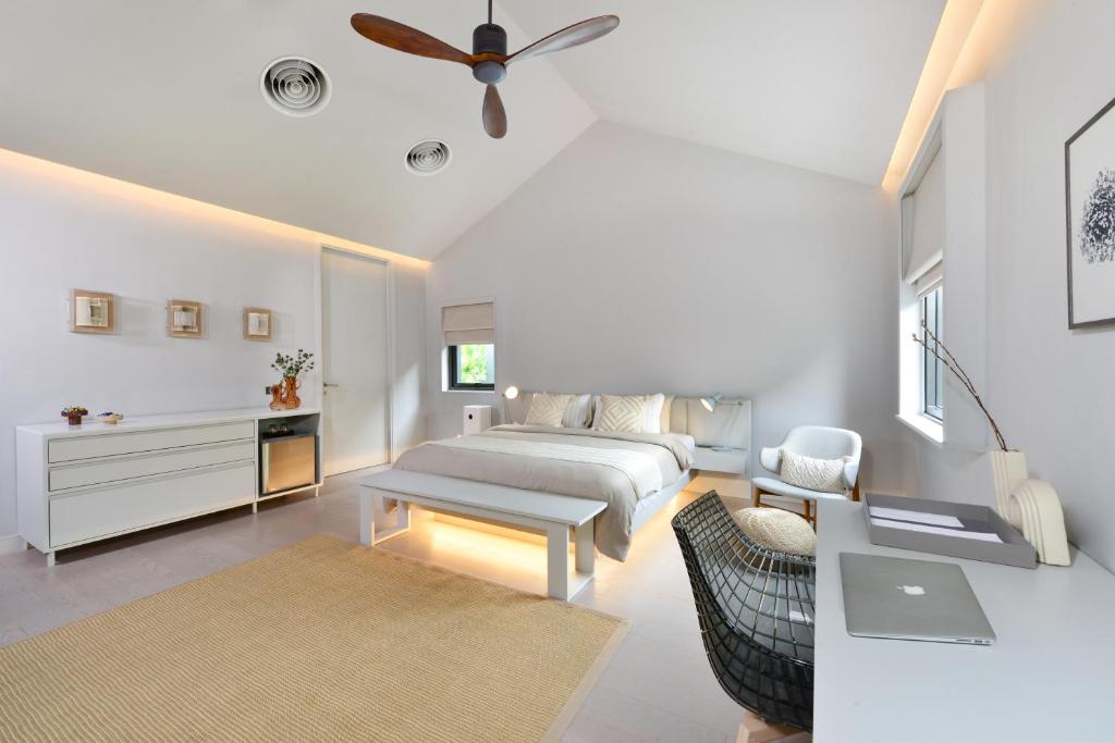 a white bedroom with a bed and a couch at Tree Villa Bangkok in Bangkok