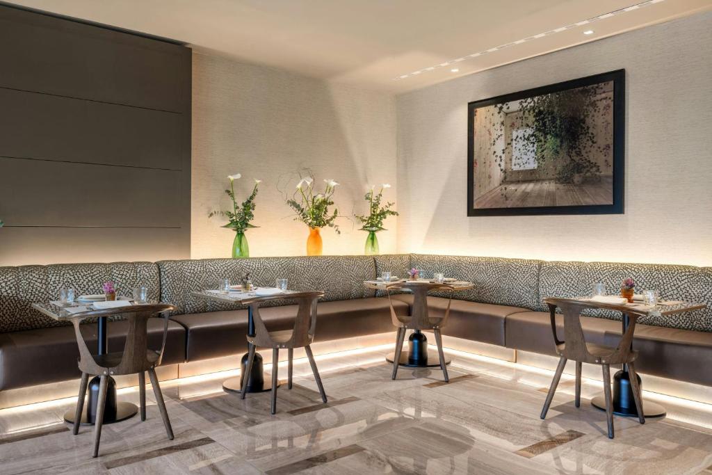 a waiting room with tables and chairs in a restaurant at AC Hotel Bologna by Marriott in Bologna