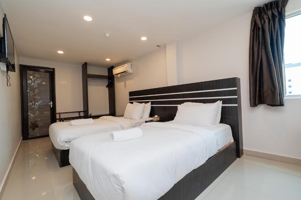 two beds in a hotel room with white sheets at Swing & Pillows - Klebang, Melaka in Malacca