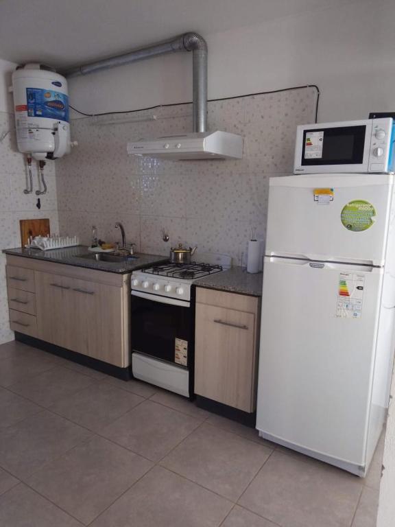 a kitchen with a stove and a white refrigerator at Cabañas moye in Santa Rosa de Calamuchita