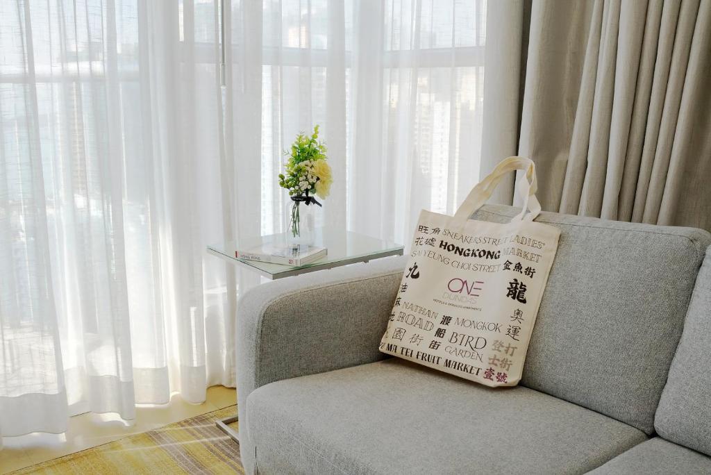 a shopping bag sitting on a couch next to a window at One Dundas Serviced Apartments in Hong Kong