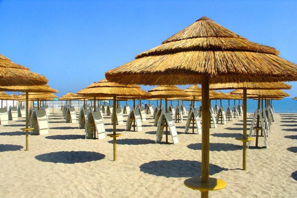 un gruppo di ombrelloni di paglia su una spiaggia di Hotel La Terrazza a Barletta