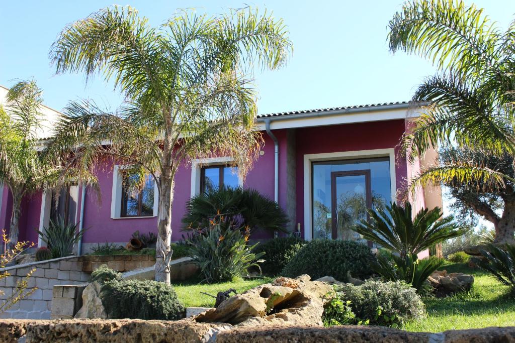 ein rosafarbenes Haus mit Palmen davor in der Unterkunft Calìu in Marausa