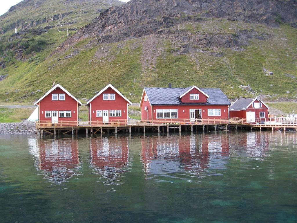 a row of red houses on a dock in the water at Sarnes Seaside Cabins in Honningsvåg