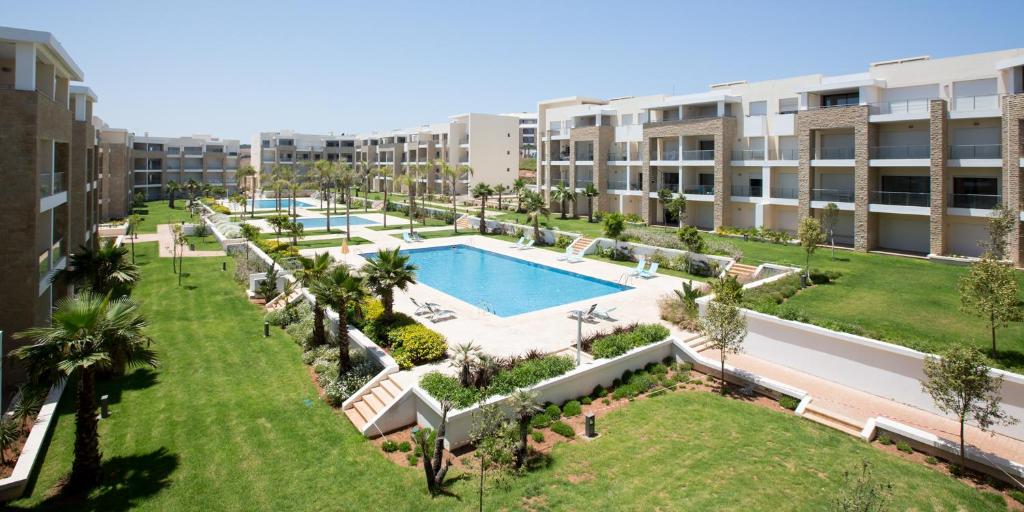 una imagen de un complejo de apartamentos con piscina en Plage Des Nations Apartment, en Sidi Bouqnadel