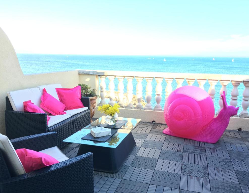 einen Balkon mit Sofa und rosa Ottomane in der Unterkunft Les Remparts Antibes Location in Antibes