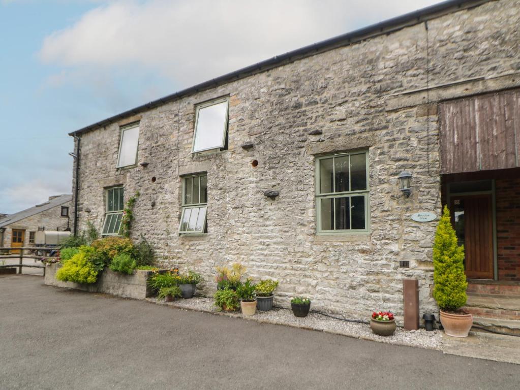 a brick building with potted plants in front of it at Meadow View in Buxton
