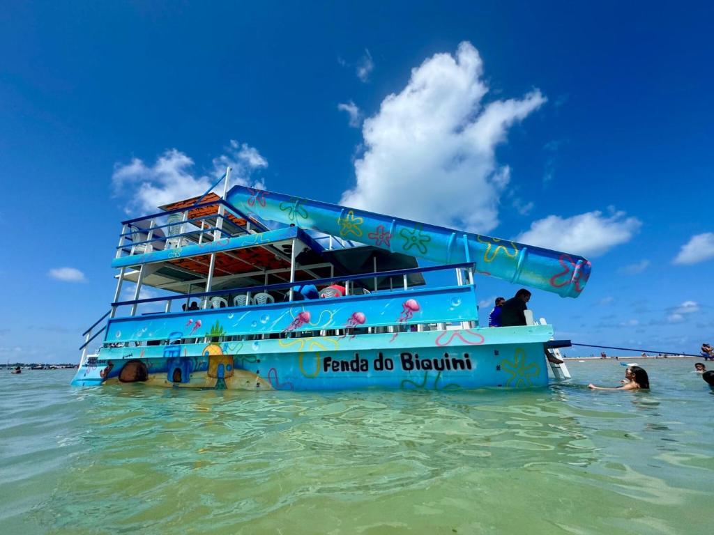 a blue boat in the water in the ocean at Catamara Fenda do Biquini in Cabedelo