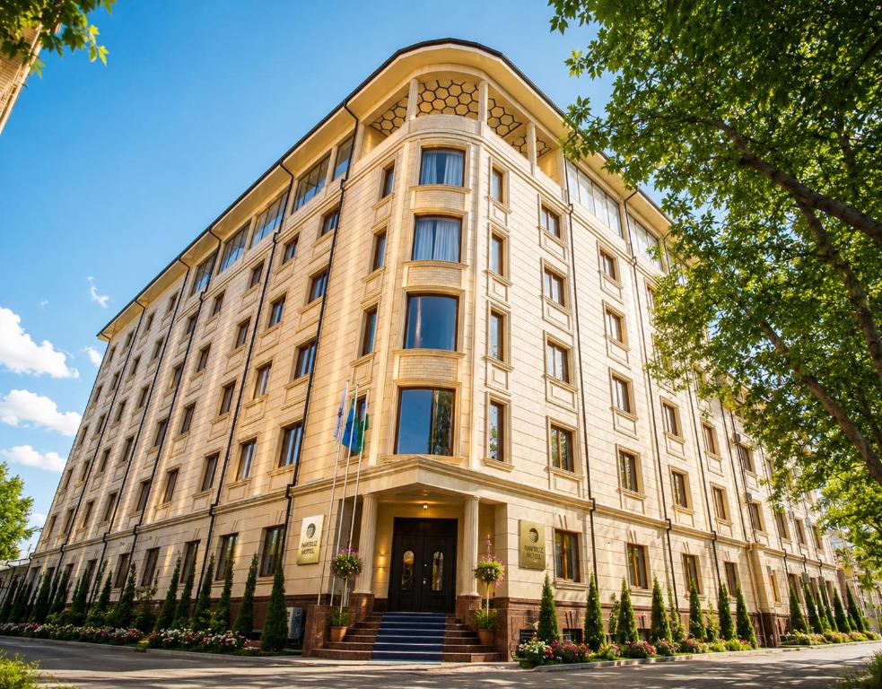 a large white building with trees in front of it at Navruz Hotel Tashkent in Tashkent