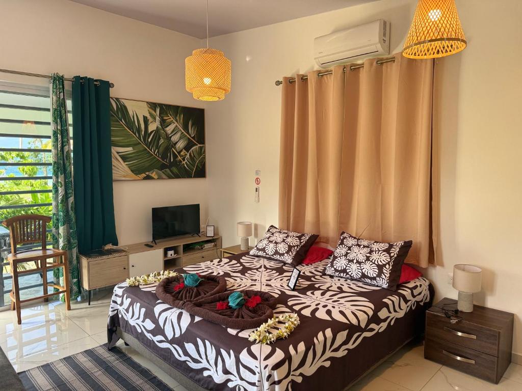 a bedroom with a bed and a television in it at Vaihi's Garden climatisé, vue sur mer - Huahine in HUH