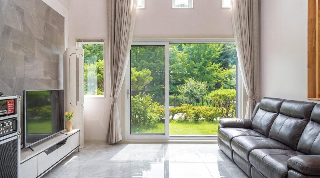 a living room with a couch and a large window at Daebudo Freesia Private Pool Villa in Ansan